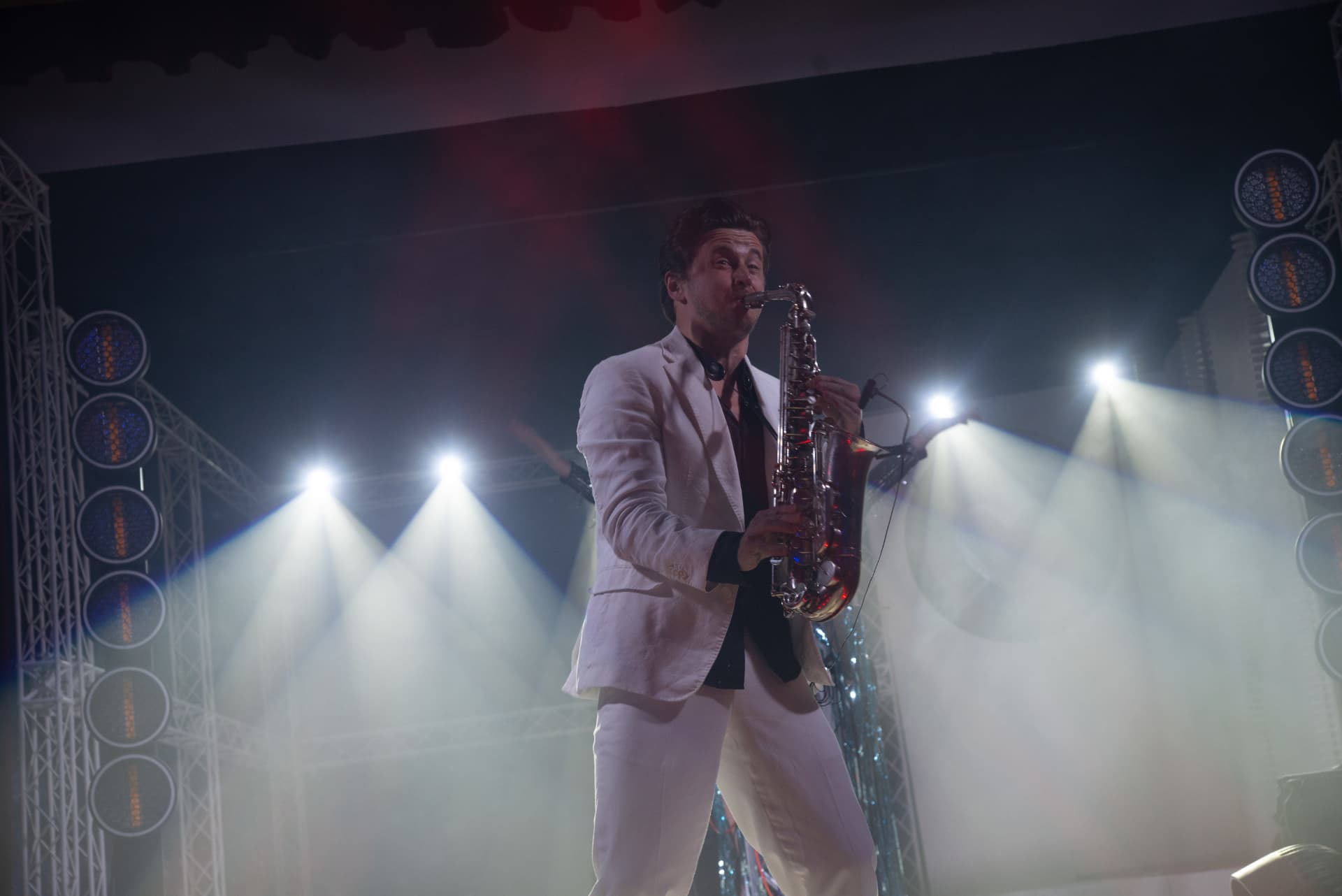 Saxofonist im weißen Anzug auf der Bühne im Scheinwerferlicht